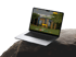 Ein offener Laptop auf einem dunklen Felsen mit einer Website, die ein modernes Haus zeigt.