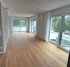 Leeres Zimmer mit Holzboden und großen Fenstern mit weißem Vorhang, blick auf die Terrasse.