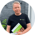 Mann in schwarzem T-Shirt mit "Semmertools"-Logo, hält Broschüre mit "Semmertools"-Titel und lächelt.