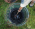 Inspector checking the inside of an open septic tank in a grassy Michigan yard