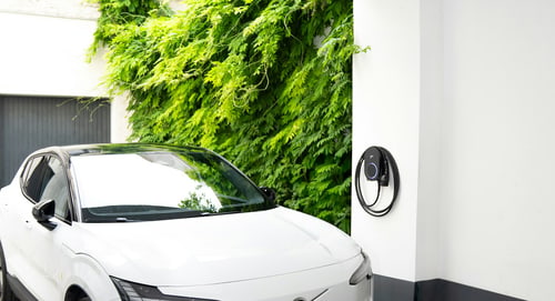 Charging an EV without a garage — an electric car charging in a Newport Beach driveway beside an outdoor wall-mounted charger