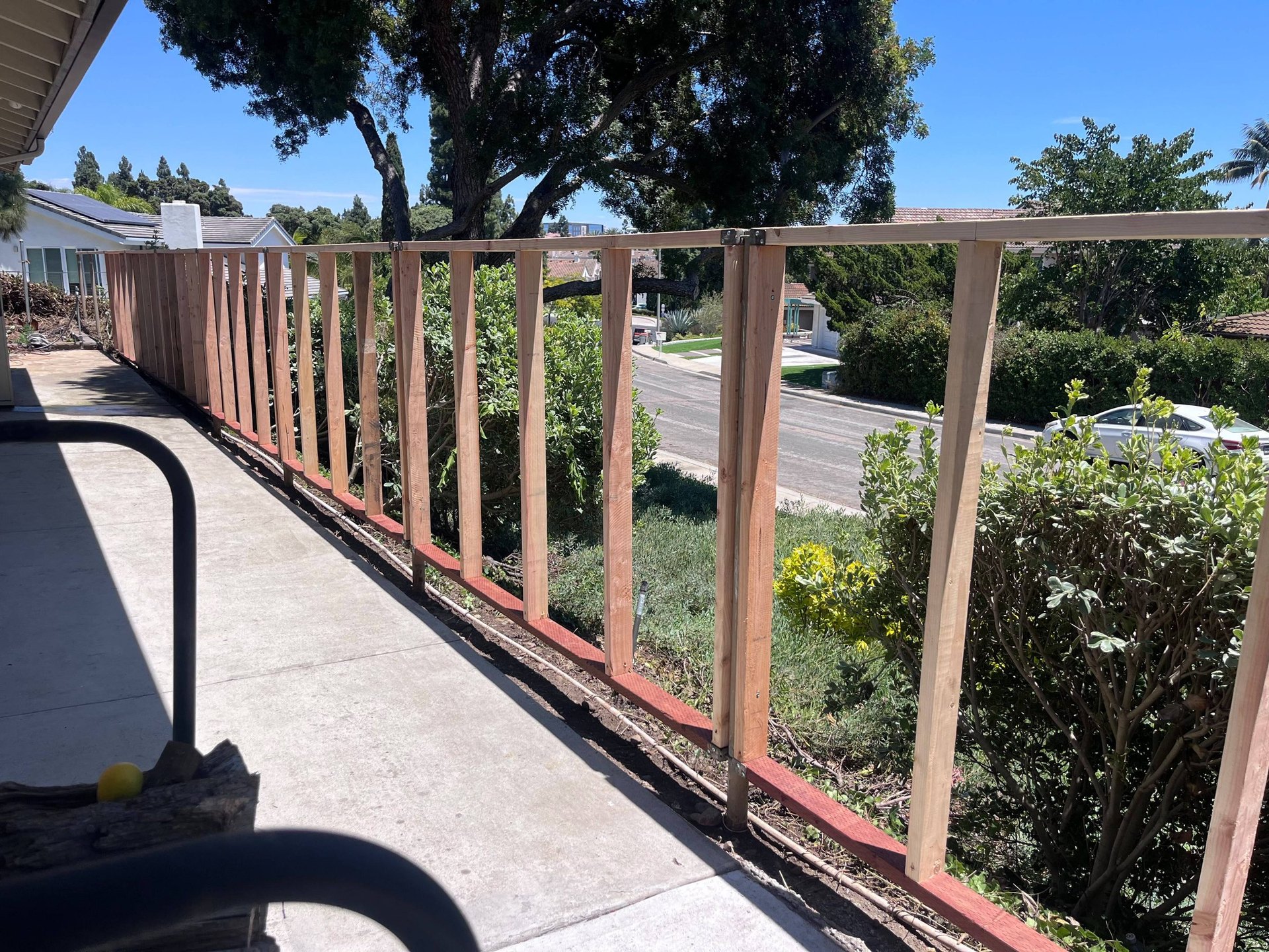 Fence framing along a side yard walkway before Hardie panel installation in San Diego