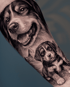 Schwarz-weißes Tattoo auf einem Unterarm, das ein detailliertes Porträt eines Hundes und eines Welpen zeigt.