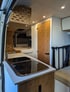 Innenausbau eines Campervans mit Küche, Bett und Holzdetails – moderner, funktionaler Vanlife-Grundriss für komfortables Reisen