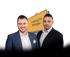 Philipp Kinnemann und Dominik Blattmann in Business-Kleidung vor dem Ortsschild von Freiburg im Breisgau – professionelle Beratung und Dienstleistungen in der Region.