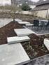 Moderne Gartengestaltung mit schwebenden Betonstufen auf Rindenmulch neben einer Terrasse mit Sitzgruppe aus Metall.
