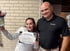 A woman holds a certificate and flowers next to a man in a black SC Medical Centers polo shirt.