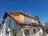 Haus mit Gerüst, rotem Ziegeldach und neuem Dachaufbau aus Holz unter blauem Himmel.