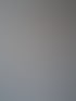 Ein lächelnder Mann mit grauem Sakko und weißem Hemd vor einer Glasbausteinwand.