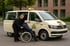 Ein Taxifahrer schiebt einen Mann im Rollstuhl zu einem beigen Taxi mit der Aufschrift "BIETA TAXI 97111".