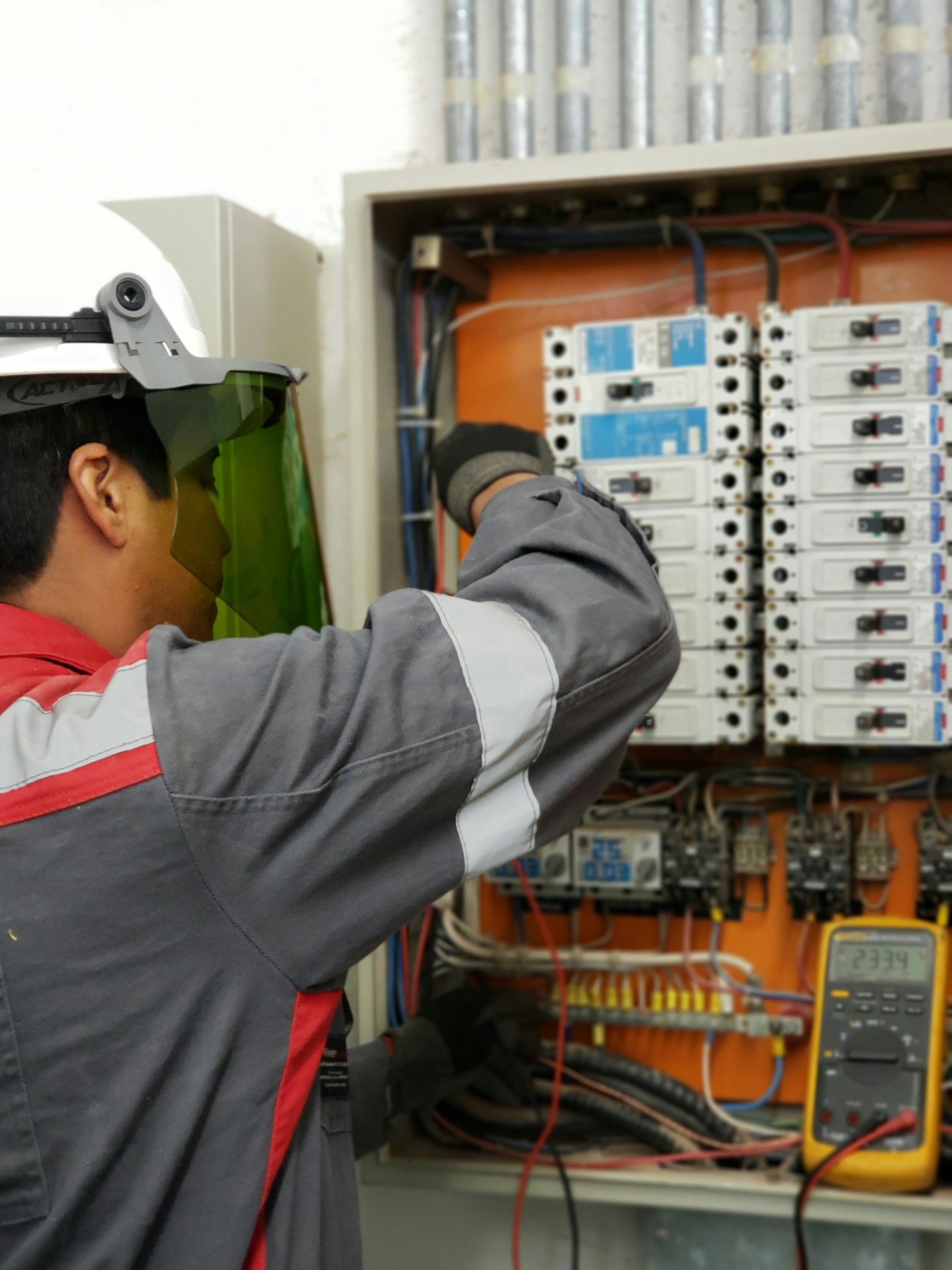 Electrician in protective gear testing a residential electrical panel