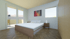 Modernes Schlafzimmer mit Doppelbett, Fischgrätparkett, zwei Nachttischen und Zugang zum Balkon.