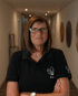 Eine Frau mit Brille und braunen Haaren trägt ein schwarzes Poloshirt mit einem weißen Logo und dem Text "BES".