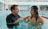 Ein Mann im schwarzen Rashguard spricht mit einem jungen Mann mit Schwimmbrille im Pool.