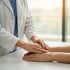 A doctor's hands placed over a patient's hands to ease neuropathy.