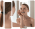 Woman touching her cheek while looking at her reflection, enjoying the results of a vampire facial.