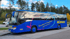 Blauer Reisebus "HÜBNER Reisen" mit Herzlogo und Text "Reisebüro & Omnibusse" auf Parkplatz.