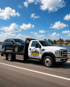 Towing Port Charlotte flatbed tow truck transporting an SUV along a coastal road in Florida.