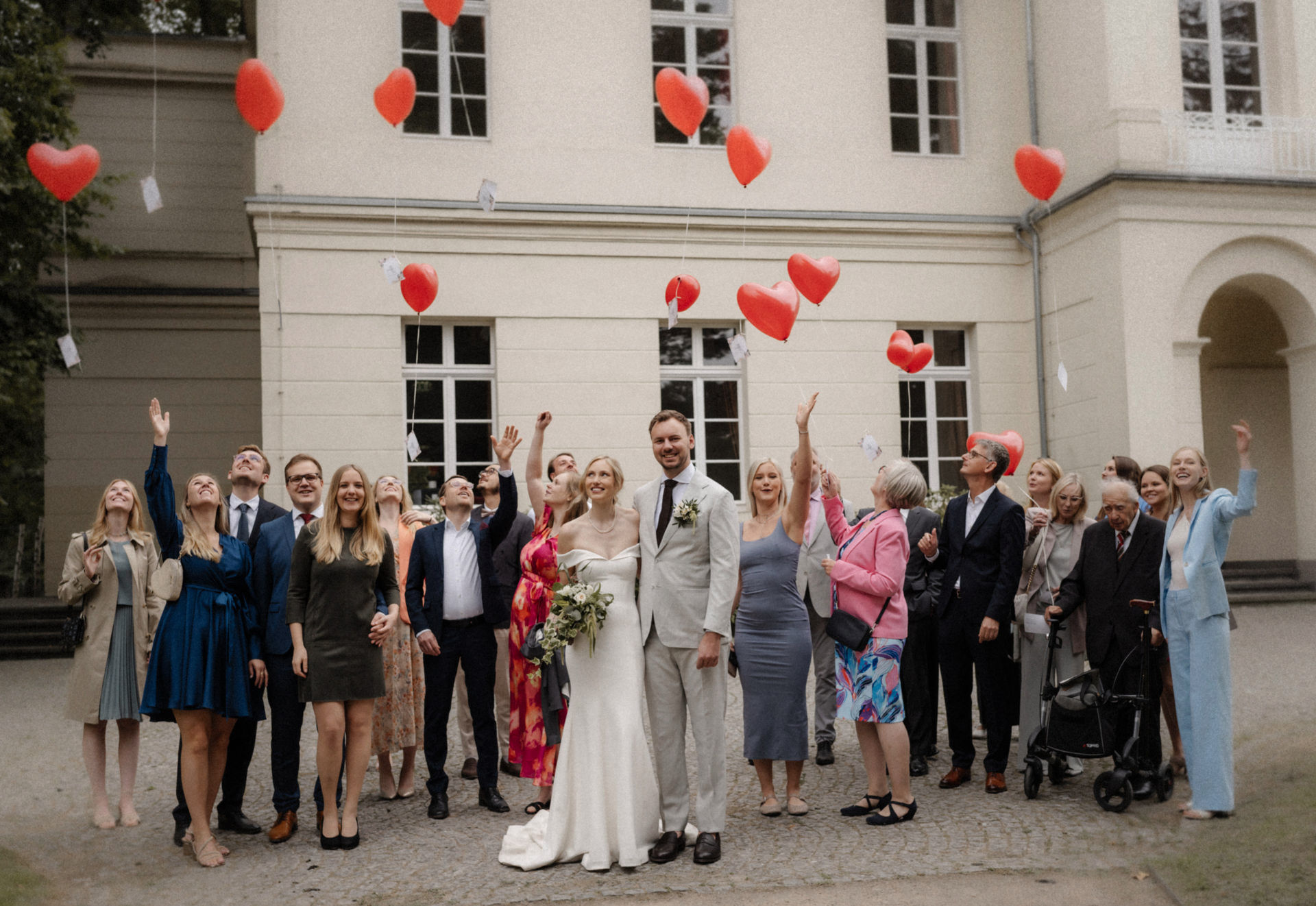 Hochzeitsgesellschaft lässt Herzluftballons vor dem Schloss Eller in Düsseldorf steigen.