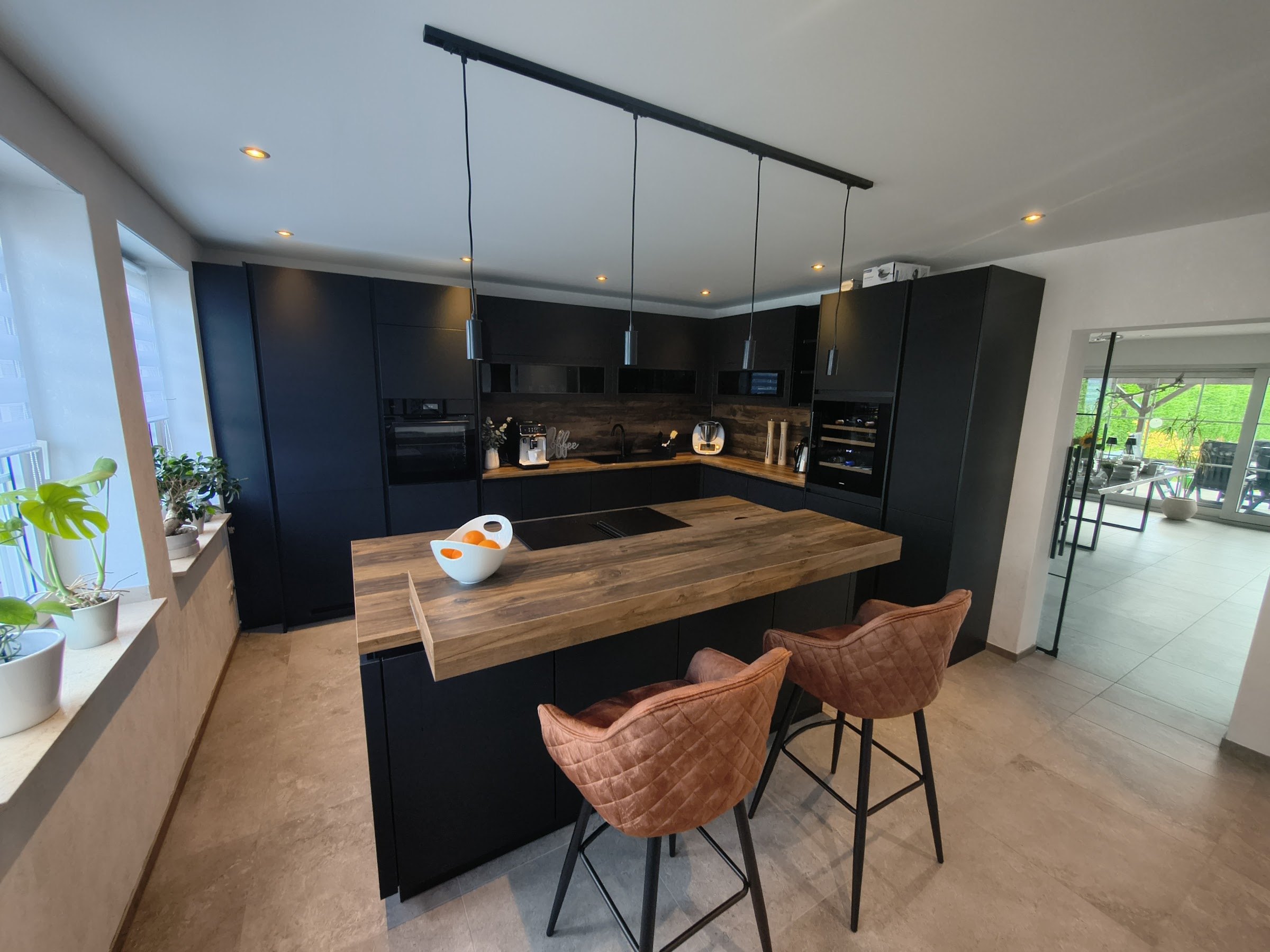 Von Baaler Küchenstudio Heinsberg geplante und montierte Küche in Schwarz mit Holztresen und Kochinsel