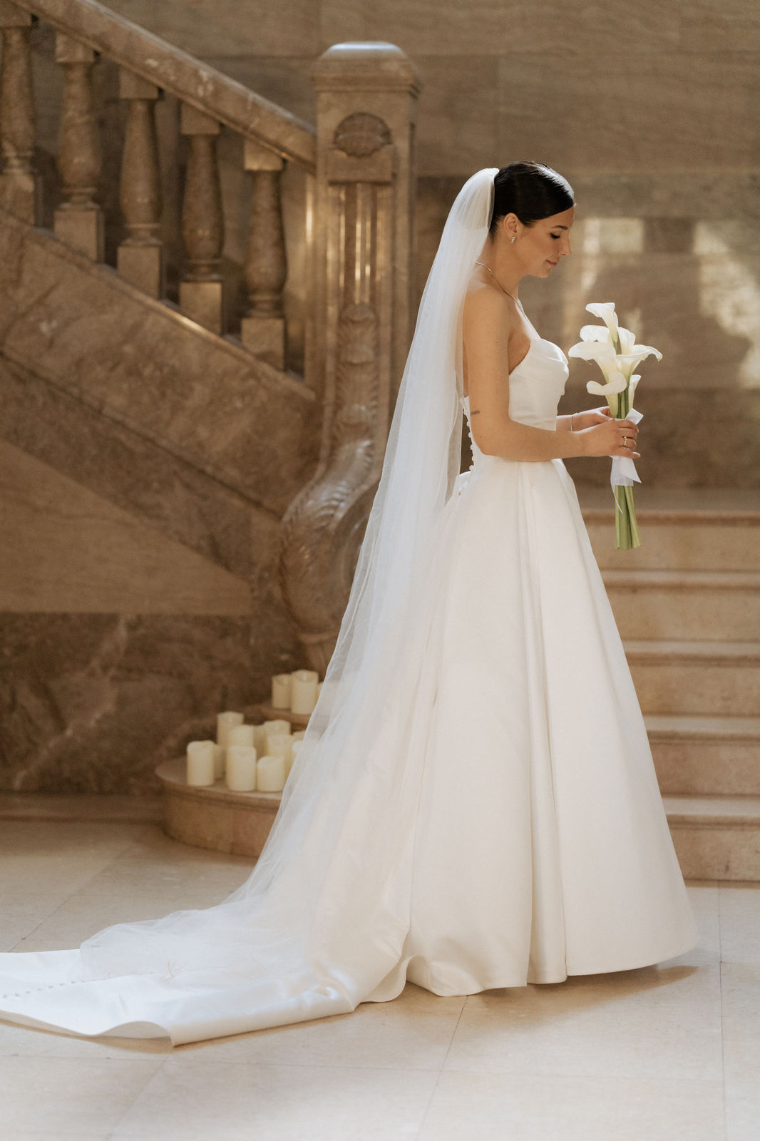 Braut im Brautkleid auf der kerzengesäumten Treppe von Schloss Garath.