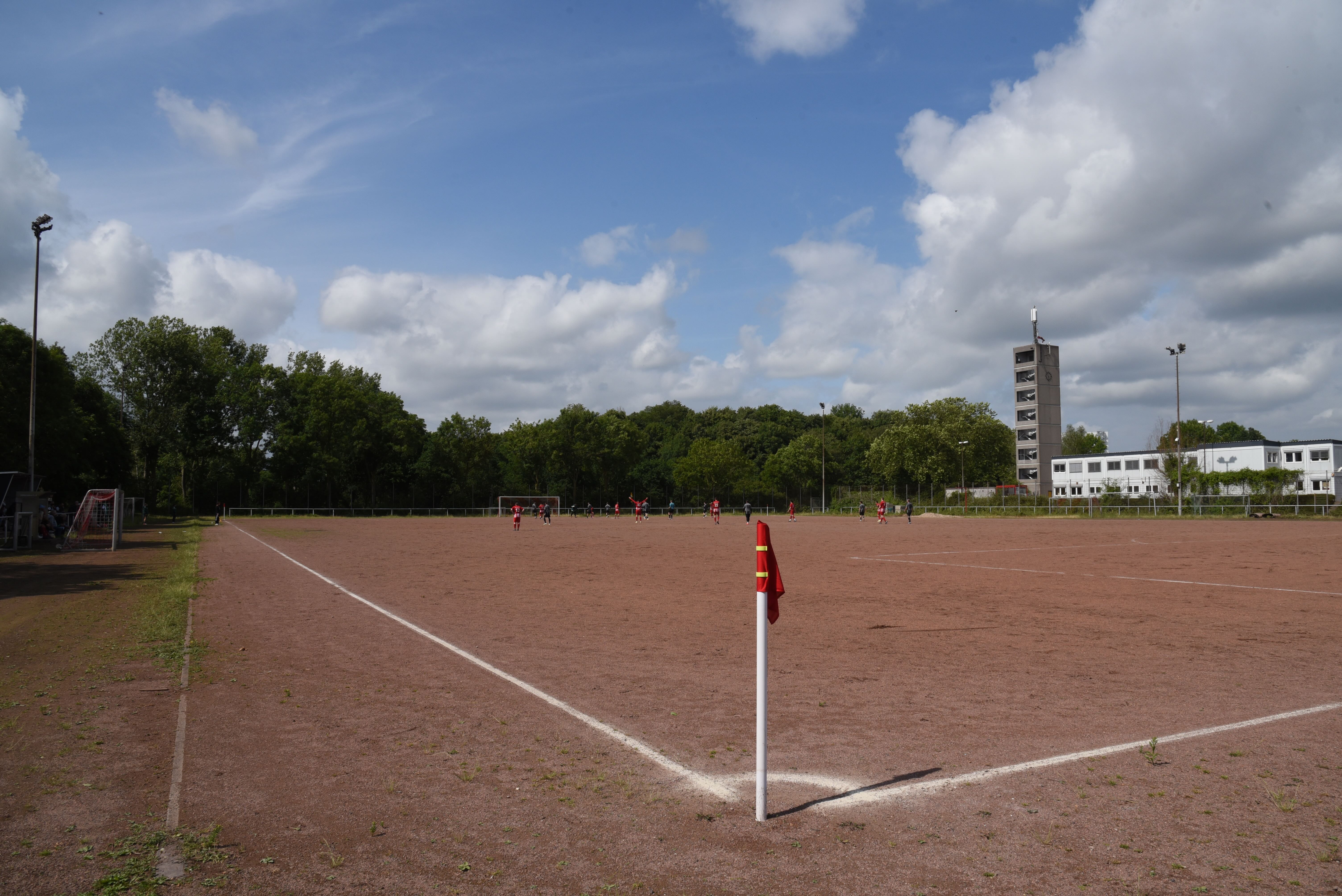 Spielfeld mit weißen Linien und angrenzender Leichtathletik-Anlage