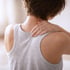 A person in a gray tank top holds their shoulder in pain.