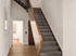 Moderne graue Treppe mit Holzhandlauf in einem hellen Flur mit Parkettboden.