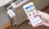 Hand hält Smartphone mit Energieeffizienzlabel-App vor einem Heizkörper.