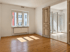 Leerer Altbau-Raum mit Dielenboden, weißen Wänden, Fenster und einer geöffneten Flügeltür zum angrenzenden Zimmer.