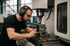 Mann mit Schutzbrille und Gehörschutz bedient eine CNC-Fräsmaschine.