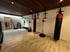 Fitnessraum mit drei Boxsäcken, Sprossenwand und Holzboden unter dunkler Holzdecke.