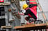 Bauarbeiter mit gelbem Schutzhelm bearbeitet eine Schalungswand aus Metall mit einem Hammer auf einer Baustelle.