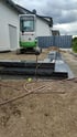 Ein Minibagger von Takeuchi auf einer Baustelle mit frisch gesetzten, dunklen Naturstein-Blockstufen im Gartenbau.