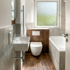 Modernes Badezimmer mit Waschbecken, WC vor Holzwand, Badewanne, grauen Fliesen und Fenster.