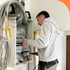 Ein Elektriker mit Messgerät arbeitet an einem offenen Sicherungskasten mit vielen Kabeln.