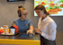 Eine McDonald's-Mitarbeiterin mit Headset zeigt einer Kollegin ein Touchscreen-Display.