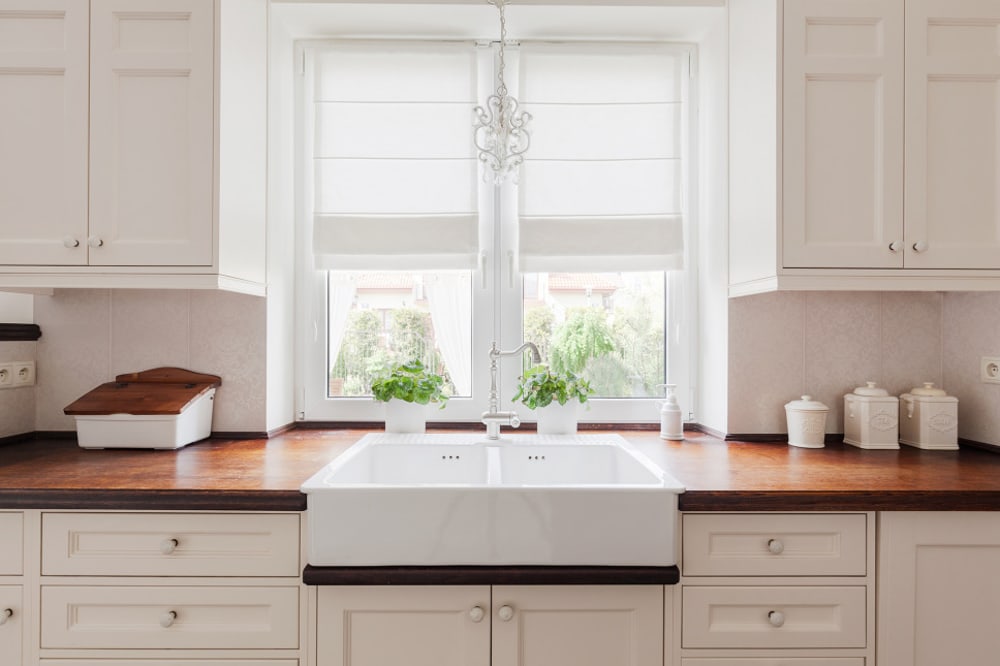 Modern white kitchen with a window backsplash and farmer's sink