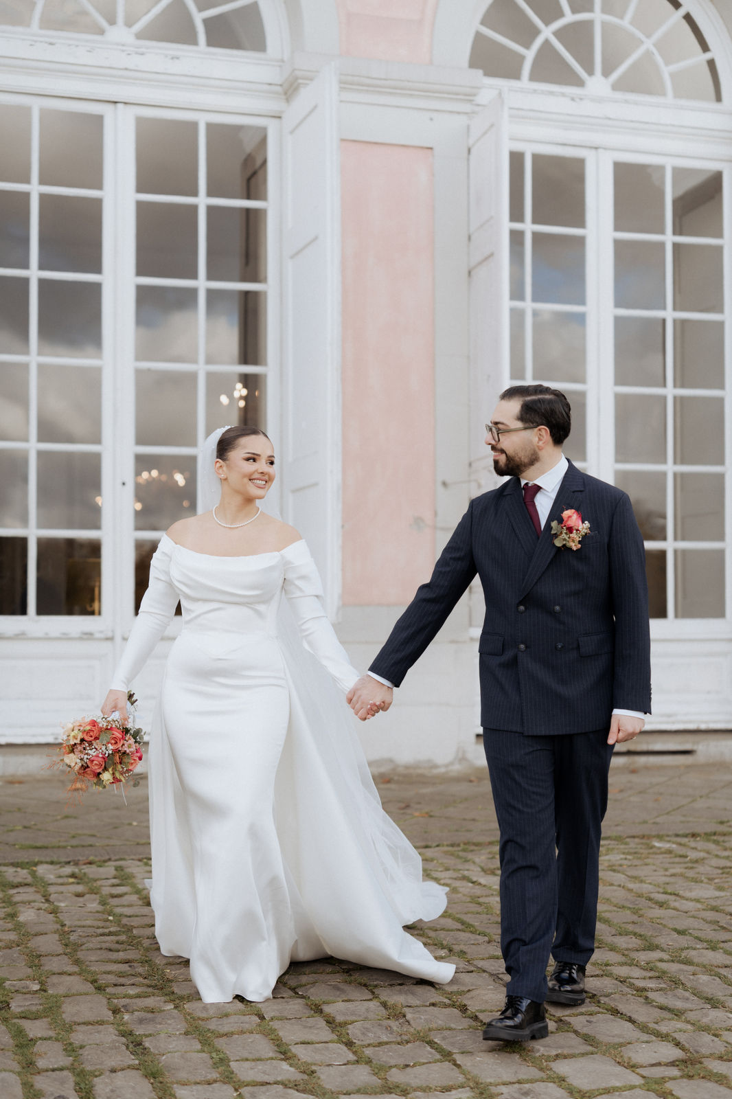 Brautpaar geht Hand in Hand über den Schlosshof von Schloss Benrath in Düsseldorf.