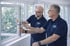 Zwei Männer in dunkelblauen Poloshirts mit BUFU-Logo montieren ein Fenster in einem hellen Raum.