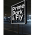Beleuchtetes Schild mit der Aufschrift „Prime Park & Fly“ in einem Parkhaus.