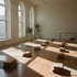 Ruhiges Yogastudio mit aufgerollten Matten und einer Massageliege in der Ecke