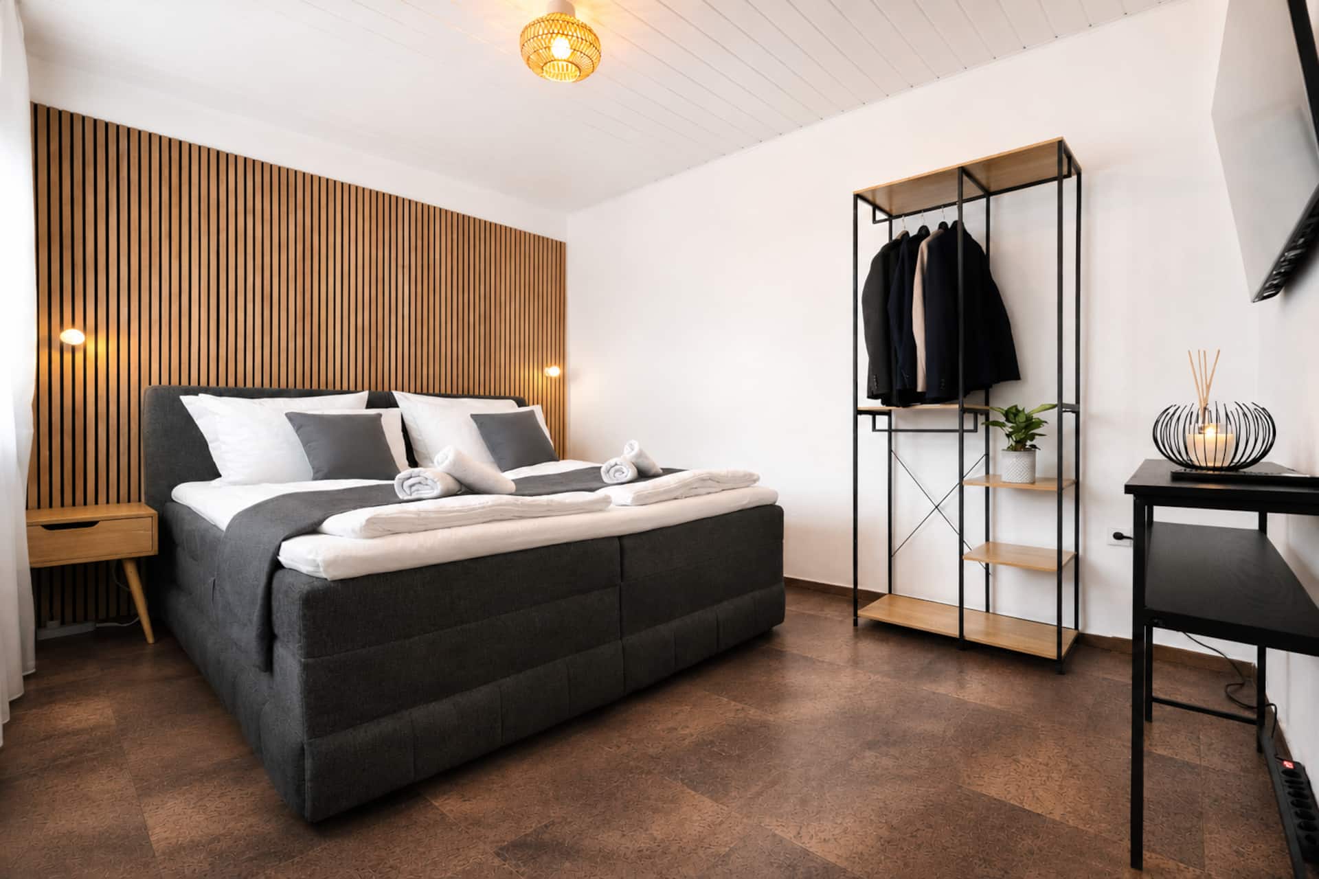 Schlafzimmer mit Doppel-Boxspringbett und Holzlamellenwand