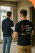 Rückenansicht zweier Männer in einem unfertigen Raum, einer mit "Das Elektro Werk" T-Shirt und Blitz-Logo.