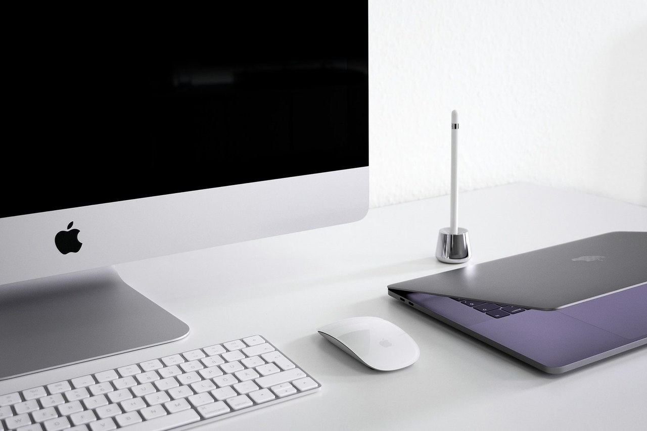 iMac und MacBook auf einem weißen Schreibtisch mit Tastatur und Maus