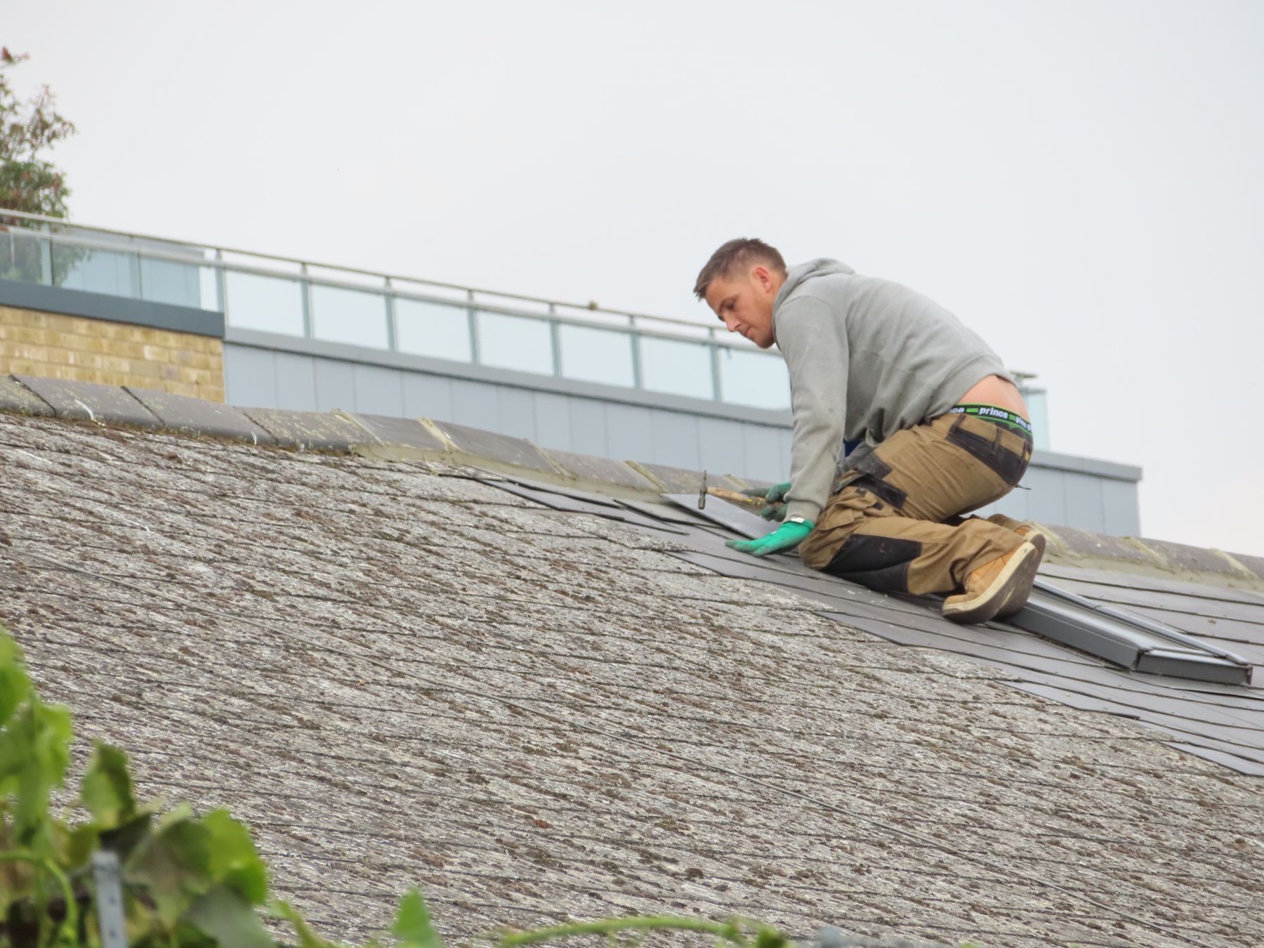 Roofer fastening shingle courses on a residential rooftop