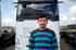 Mann mit gestreiftem Hemd steht vor einem weißen Volvo-LKW.