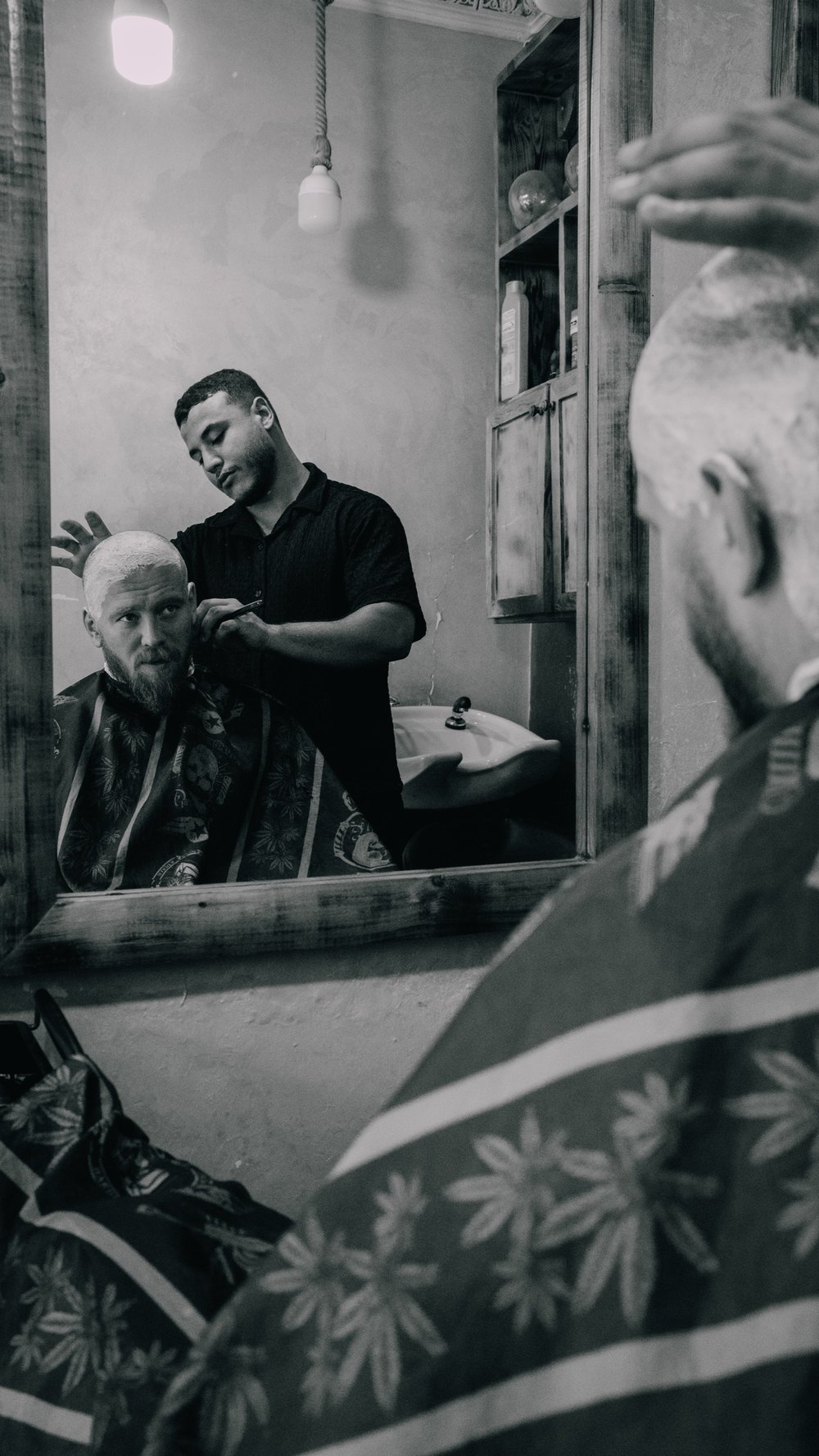 Friseur schneidet einem Kunden die Haare, Spiegelbild in Schwarz-Weiß