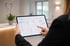 Eine Person bedient in einer Zahnarztpraxis ein Tablet mit einem Dashboard für Praxismanagement und Statistiken.