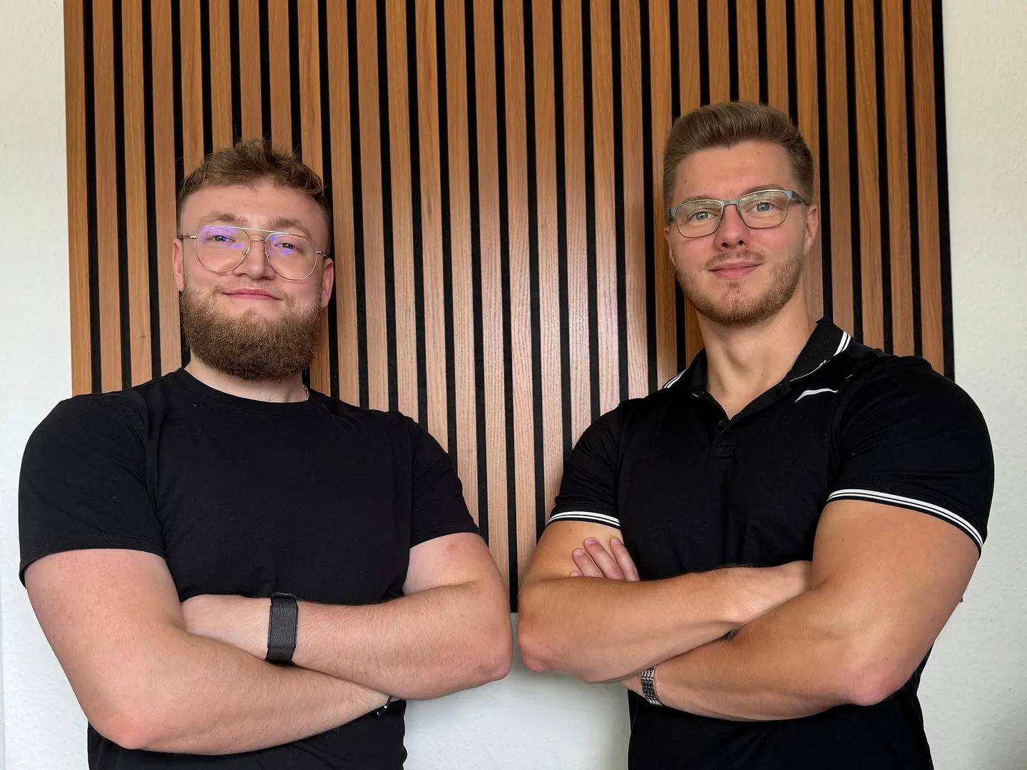 Philip Geistlinger (links) und Niklas Maiwurm (rechts), die Gründer von Mailinger Marketing, vor einer Holzlamellenwand